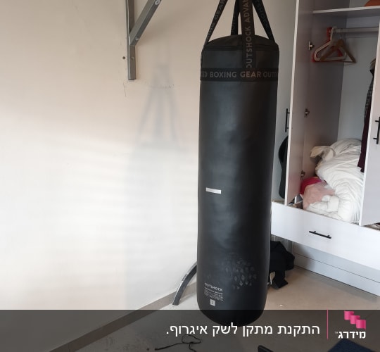 שק אגרוף תלוי על קיר בחדר עם ארון פתוח
